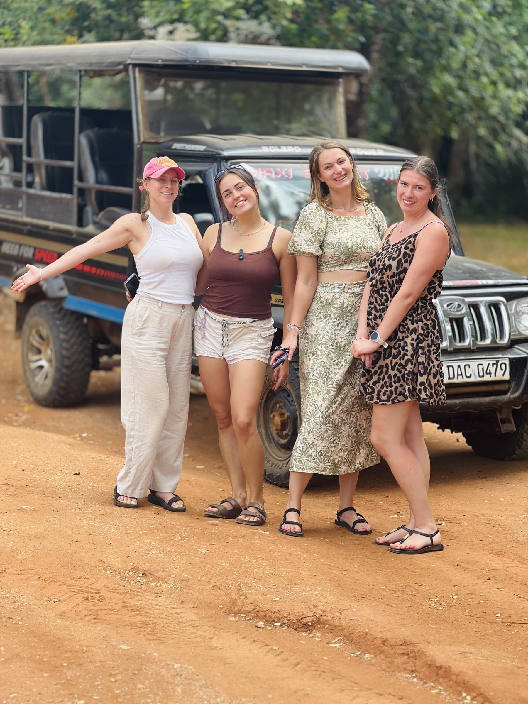 A group of friends posing beside the safari jeep