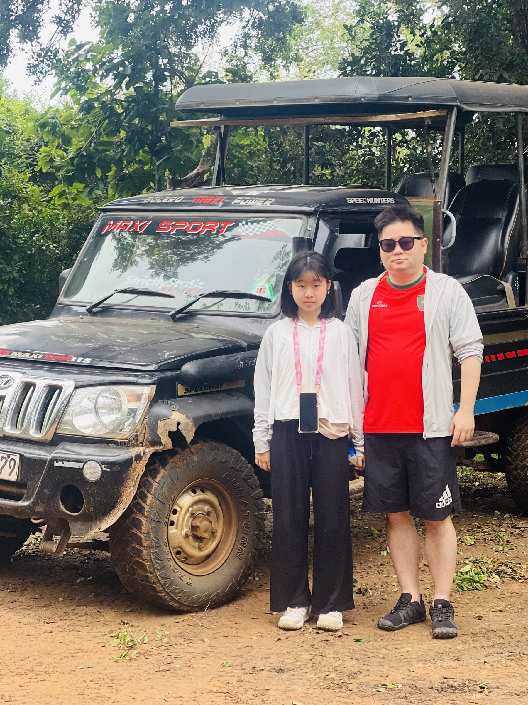 A guest and her daughter posing beside the safari jeep